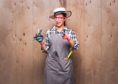 Bahçıvan kadın seni vurmaya hazırlanıyor. Stüdyoda tahta arka planda silah gösteren güzel bir kadın çiftçi. Stüdyo çekimi