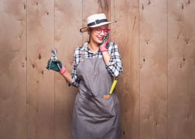 Stüdyoda ahşap arka planda güzel bir konsepte poz veren kapalı gözlü güzel bir kadın çiftçi. Güzel, genç bahçıvan kadın ellerini yanaklarından ayırmıyor. Stüdyo çekimi