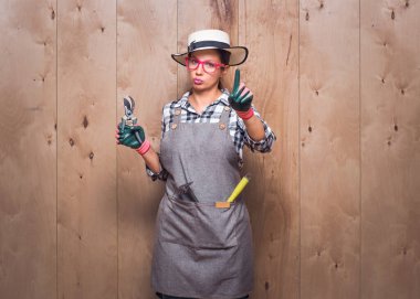 Hadi canım. Bahçıvan kadın, stüdyodaki ahşap arka planda parmağıyla işaret vermiyor. İçki yasağı ya da jest konsepti. Stüdyo çekimi