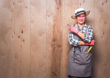 Sunum. Bahçıvan kadın boş alanı işaret ediyor. Kopya alanı. Stüdyoda ürününüzü ahşap arka planda sunan kadın çiftçi. Tanıtımcı metnin için boşluk gösterir. Stüdyo çekimi