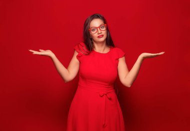 Çözüm. Kolları açık genç bir kadın kırmızı arka planda izole edilmiş bir şekilde seçim yapmanıza izin veriyor. Stüdyo çekimi