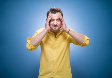 Yanlışlık. Onun ellerini kafasında tutan endişeli genç adam. Unutma, mavi arka planda unutulmuş bir konsept, sarı gömlekli. Stüdyo çekimi