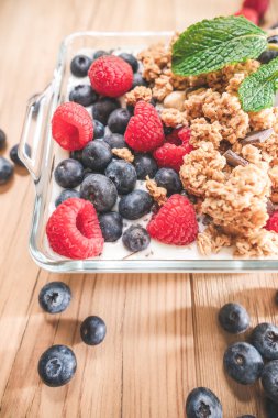 Sütlü tahıllar ve yabani meyveler. Cam kasede sağlıklı yemek.