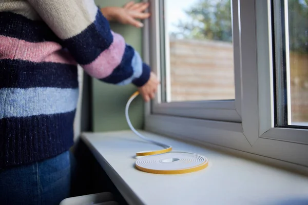 妇女拯救绝热保暖家庭在窗户上贴上止气带 — 图库照片