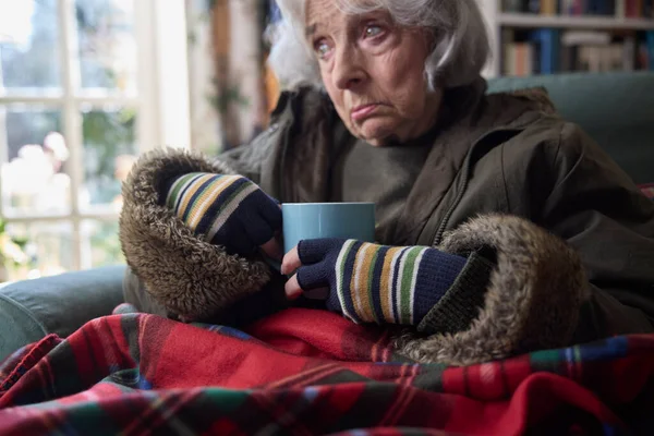 在能源危机中 穿着热饮外套的老年女性居家取暖的特写镜头 — 图库照片