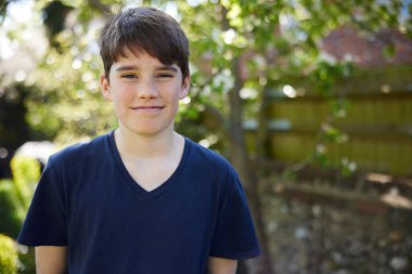 Portrait Of Smiling Teenage Boy In Garden At Home