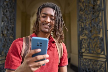 Oxford İngiltere 'deki üniversite binasının dışındaki cep telefonundan mesajları ya da sosyal medyayı kontrol eden erkek öğrenci