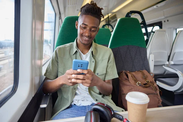 stock image Young Man Commuting To Work On Train Sitting  On Train Looking At Mobile Phone For Travel Information Or Social Media