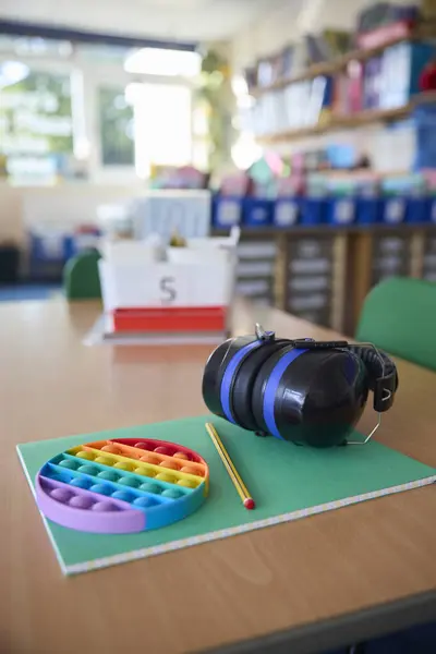 Ear Defenders Or Headphones And Fidget Toy To Help Child With ASD Or Autism On Table In School Classroom