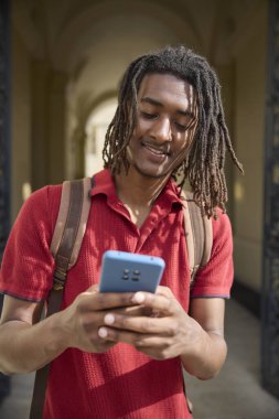 Oxford İngiltere 'deki üniversite binasının dışındaki cep telefonundan mesajları ya da sosyal medyayı kontrol eden erkek öğrenci