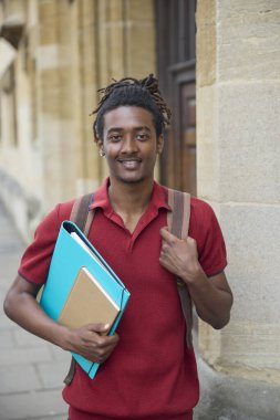 Oxford İngiltere 'deki Üniversite binasının dışında dosya taşıyan erkek öğrencinin portresi.