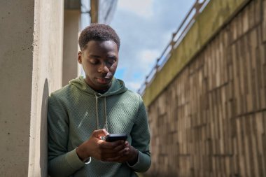 Sosyal medya ya da mesajları şehir merkezinin dışındaki cep telefonundan kontrol eden genç çocuk.