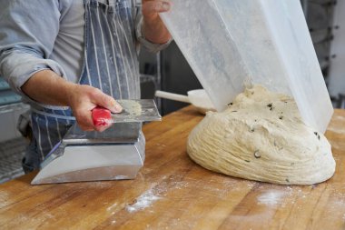 Fırını kapatıp hamuru kesip tartmaya hazırlanan fırında kendi somunlarını yapmaya hazırlanan fırını kapatın.