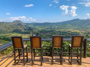 Tayland 'ın Phayao eyaletinin kırsal kesimindeki manzaralı dağ manzaralı balkonda yüksek bar tabureleri. Turistler için tahta sandalyeler Phu Lang kha ormanına, doğa manzarasına, köye, tarlaya baksınlar..