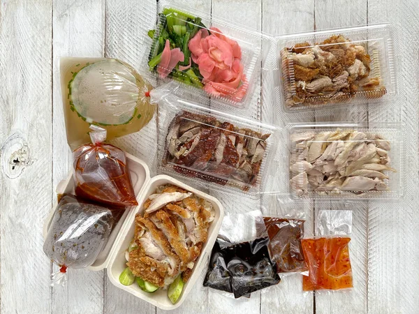 海南鸡饭 汤和酱料在塑料和食品级工艺纸包装容器的木制背景 餐馆提供的各种健康的街头食品的顶级视图取消了在Asi提供的在线服务 — 图库照片#