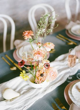 Güzel bir yemek masası beyaz bir vazoda çiçek aranjmanı içerir. Zarif yemekler ve cam eşyalar, davetkar bir atmosfer yaratmak için özel bir toplantı düzenlenir..