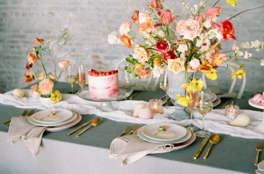 Canlı bir masa çarpıcı bir çiçek aranjmanı, hassas yemekler ve pembe bir pasta ile süslenir. Bahar toplantısı için davetkar bir ortam yaratır..