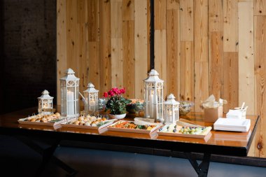 Dekoratif fenerlerle ahşap tepsilerde çeşitli aperatiflerin sergilendiği davetkar bir büfe..