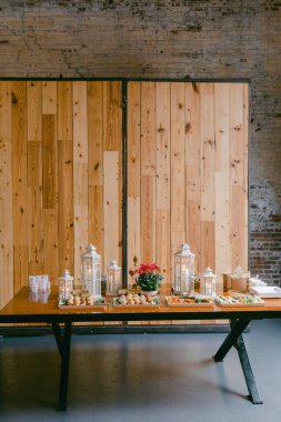 Güzel düzenlenmiş bir açık büfe masasında, büyüleyici fenerler ve kırsal bir ortamda bir çiçek süsü ile çevrili çeşitli hamur işleri ve tatlılar sergilenir..