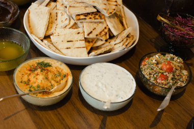 Humus, tzatziki ve tabbouleh de dahil olmak üzere geleneksel Orta Doğu aperatiflerinin canlı bir gösterisi ve yanında taze ızgara ekmek. Ortam sıcak ve davetkar, paylaşmak için mükemmel..