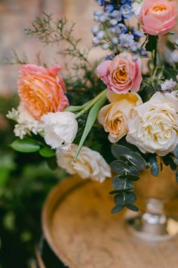 Pembe, turuncu ve beyaz gülleri de içeren canlı bir çiçek koleksiyonu, güzel bir kırsal vazoda serpilmiş, büyüleyici bir ortamda yemyeşil bir vazoyla çevrili..