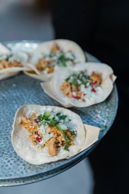 Baharatlı tavuk, taze otlar ve sebzelerle dolu tacolar, akşam karanlığında şehirdeki bir açık hava etkinliği sırasında dekoratif bir tabakta sunuluyor..