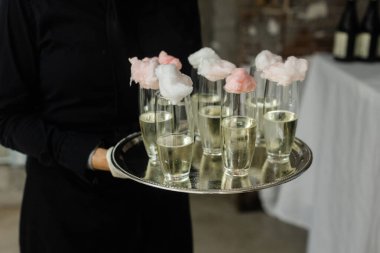 Köpüklü içecekler renkli pamuk şekerlerle kaplı bir tepside sunulur, kırsal bir mekanda şenlikli bir toplantıda. Misafirler yaratıcı ve eğlenceli şeylerden hoşlanırlar..