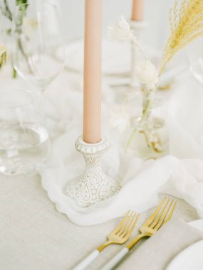 Dekoratif tutacaklarda pastel mumlar sergileniyor. Zarif çiçek dekoru ve zarif cam süslemelerle çevrili..