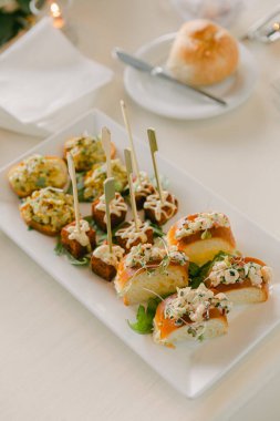 Gourmet aperatifleri beyaz tabakta, yaratıcı tatlar ve bir akşam etkinliği için zarif bir sunumla sunuluyor..
