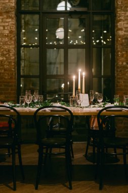 Güzel hazırlanmış yemek masası misafirler için hazırdır. Kır ortamında mumlar hafifçe parlar..