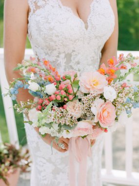 Canlı pastel çiçekler romantik bir açık hava düğün töreninde büyüleyici bir gelin buketi oluşturur..