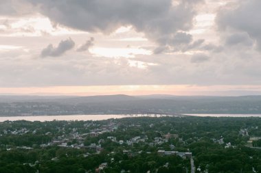 Çarpıcı bir günbatımı, ağaçlarla çevrili nehri ve dramatik, bulutlu bir gökyüzünün altında büyüleyici bir kasabayı yansıtıyor..