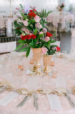 Altın vazolardaki canlı çiçekler iyi hazırlanmış bir ziyafet masasında davetkar bir ortam yaratır..