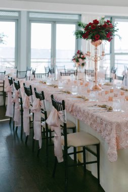 Beautifully arranged table with pink decorations and floral centerpieces overlooking a scenic landscape in daylight. clipart