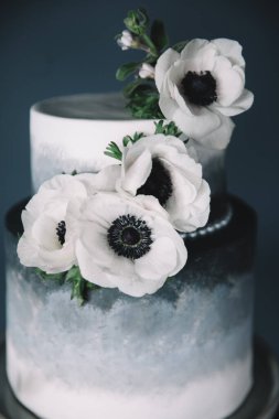 Güzelce hazırlanmış iki katlı bir pasta, narin beyaz çiçeklerle vurgulanmış, karanlıktan aydınlığa pürüzsüz bir gradyan içerir. Düğünler ya da özel durumlar için ideal, bu tatlı görsel olarak çarpıcı..