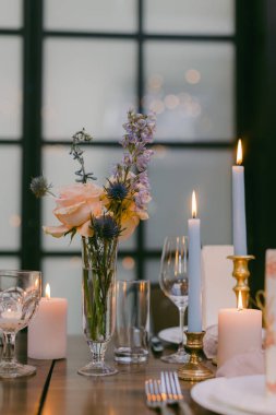 Çok güzel düzenlenmiş bir masa, canlı çiçekli bir vazo, değişik yüksekliklerde parlayan mumlar, ve parıldayan camlar, sıcak ve davetkar bir atmosfer yaratır..