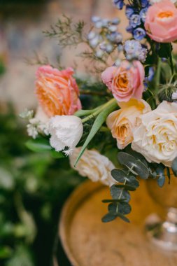 Güllerin ve diğer çiçeklerin canlı çeşitleri, yerel bir pazara baharın gelişini ön plana çıkaran, kırsal bir ahşap yüzeyde güzelce düzenlenmiştir..