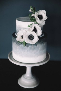 Bu göz kamaştırıcı iki katlı pasta pürüzsüz bir mezar tasarımı içeriyor ve özel durumlar ve kutlamalar için mükemmel beyaz çiçeklerle süslenmiş..