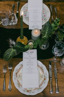 Güzel düzenlenmiş bir yemek masasında hassas porselenler, pırıl pırıl cam eşyalar ve titreyen mumlar, samimi bir toplantı için davetkar bir ortam yaratıyor..