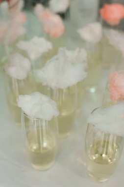 Hafif bir içecekle doldurulmuş kokteyl bardakları yumuşak pamuk şekerlerle süslenir ve gece boyunca parti atmosferine tuhaf bir dokunuş eklenir..