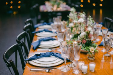 Güzel düzenlenmiş bir yemek masası güzel porselenler ve cam eşyalar, taze çiçekler, mumlar ve özel bir toplantı için sıcak bir ortam ile tamamlanmış..