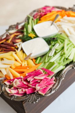 Havuç, kereviz ve turplar da dahil olmak üzere canlı bir sebze çeşidi, iki kase sosla cilalanmış bir tepside güzelce düzenlenir. Sosyal bir toplantı için mükemmeldir..