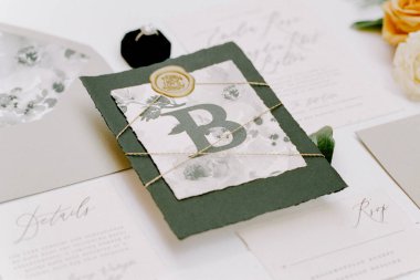 A beautifully crafted wedding invitation suite showcases a botanical design with a prominent letter B. clipart