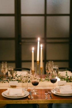 Hoş bir yemek deneyimi için mumlar, şarap bardakları ve zarif bir dekor içeren güzel bir masa..