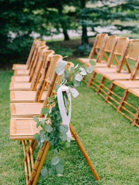 Yeşillik ve kurdelelerle süslenmiş bir düğün töreni için ayarlanmış bambu sandalyeler..