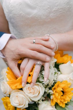 Bir çift alyans beyaz ve sarı çiçeklerle doludur. Aşkı ve bağlılığı simgeler..