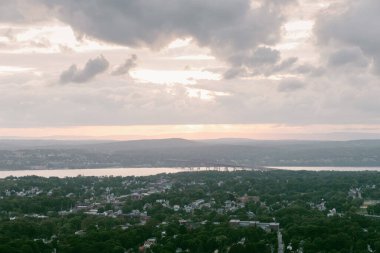Çarpıcı bir günbatımı, ağaçlarla çevrili nehri ve dramatik, bulutlu bir gökyüzünün altında büyüleyici bir kasabayı yansıtıyor..