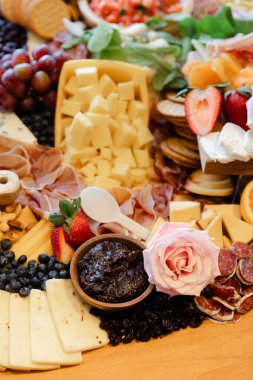 Çok güzel düzenlenmiş bir peynir tabağında çeşitli peynirler, meyveler, fındıklar ve çeşitlilik var..