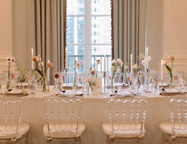 Çiçeklerin ve mumların yer aldığı güzel düzenlenmiş yemek masası güzel aydınlatılmış bir yerde şık bir ambiyans sergiliyor..