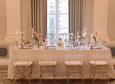 Çiçek süslemeleri, mumlar ve zarif sofra takımlarıyla çarpıcı bir yemek masası sofistike bir ortam yaratır..